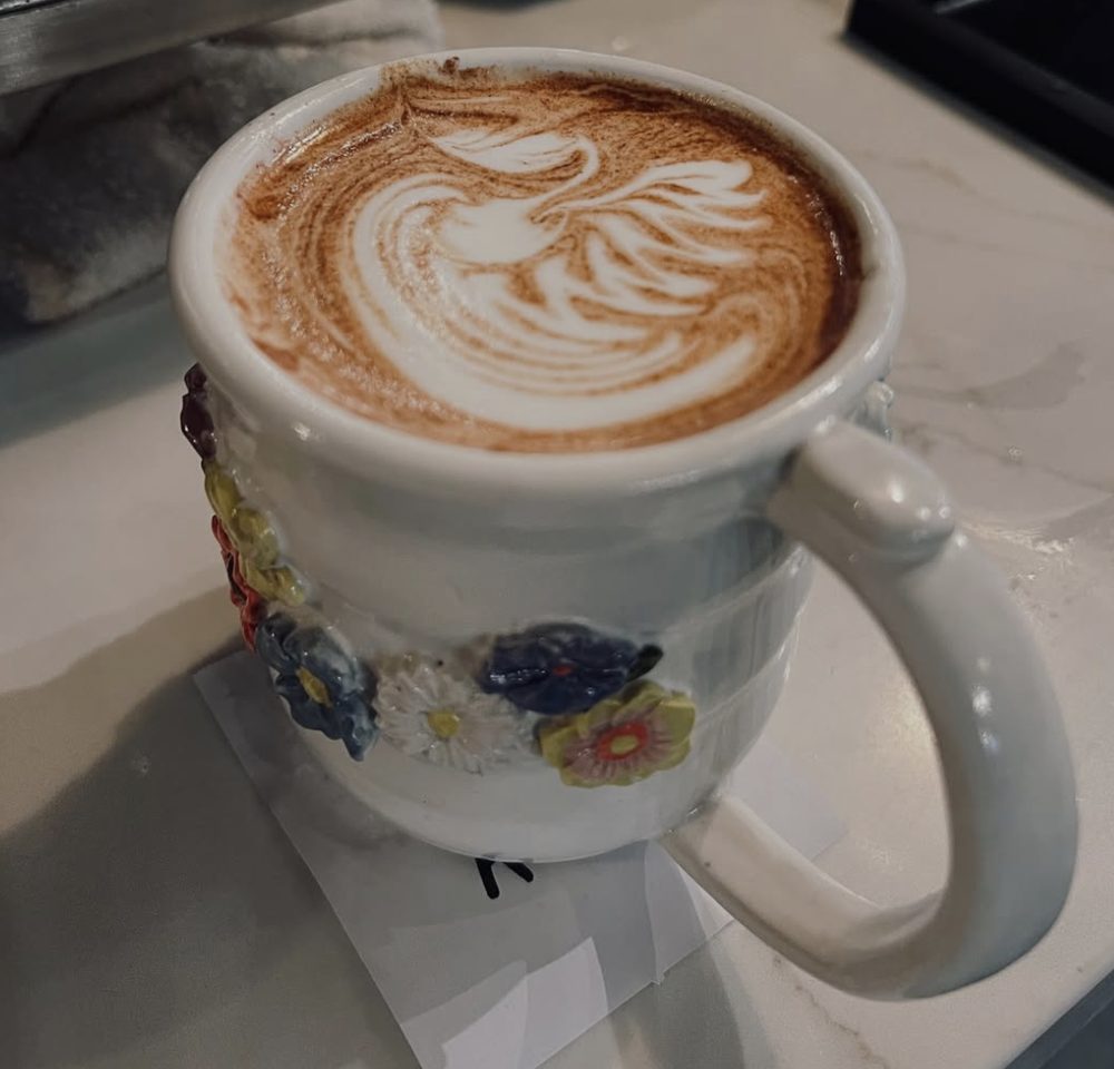 A phoenix poured in latte art, served in a hand-painted floral mug